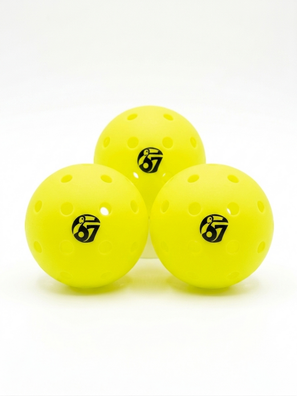 Three yellow perforated pickleballs with the number 67 logo on a white background
