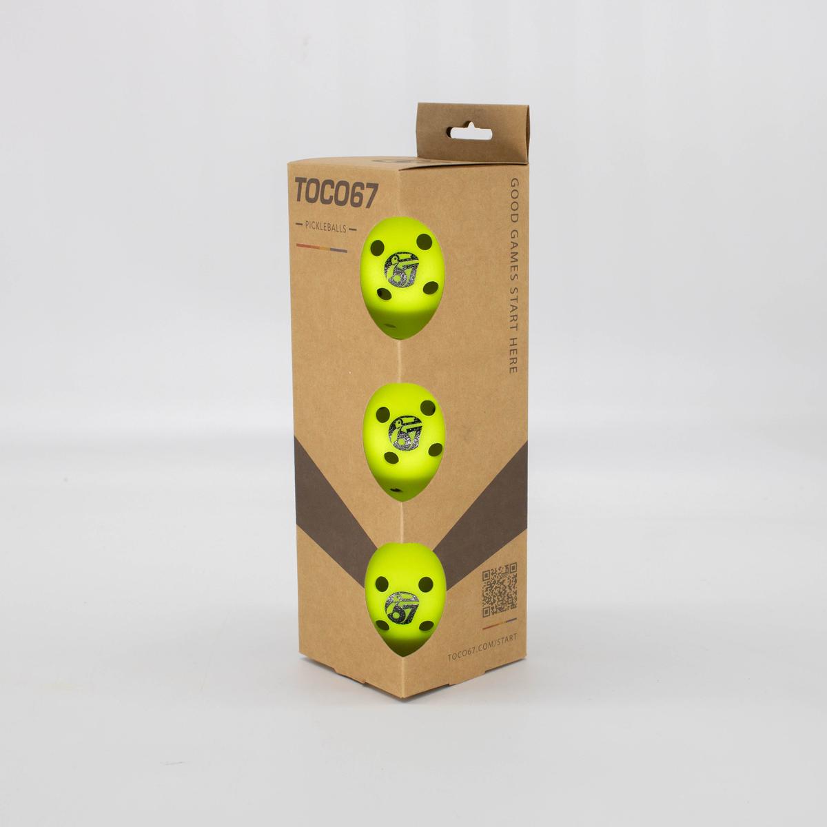 Three yellow TOCO67 competition pickleballs in a brown cardboard packaging.